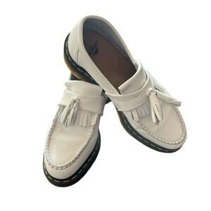White leather Dr. Martens tassel loafers.